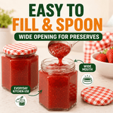 A jar of red strawberry jam shown open with a spoonful of jam being lifted, alongside another sealed jar with a red-and-white check lid and text reading 'EASY TO FILL & SPOON' and 'WIDE OPENING FOR PRESERVES.'.