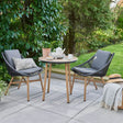 outdoor bistro set on stone patio with the garden in the background.