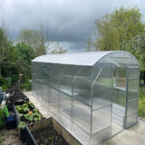 long polycarbonate  greenhouse with plants next to it