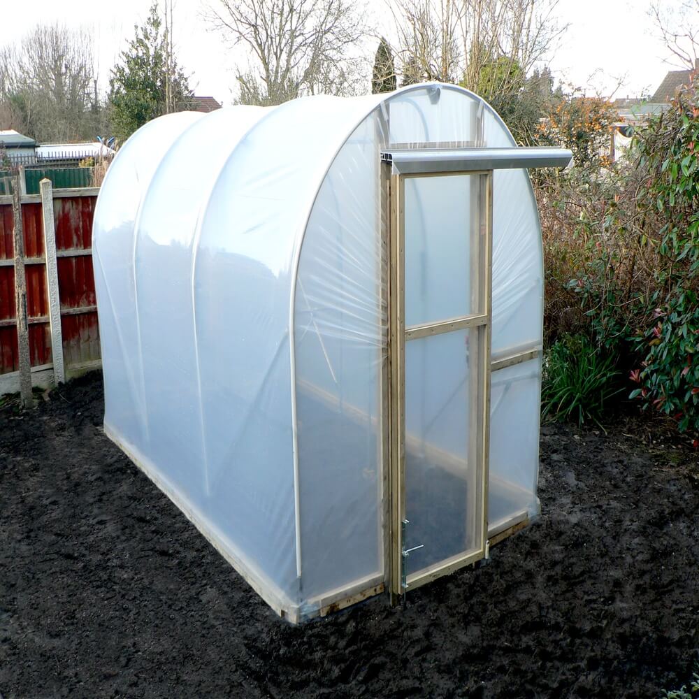 Small polycarbonate greenhouse in a garden setting