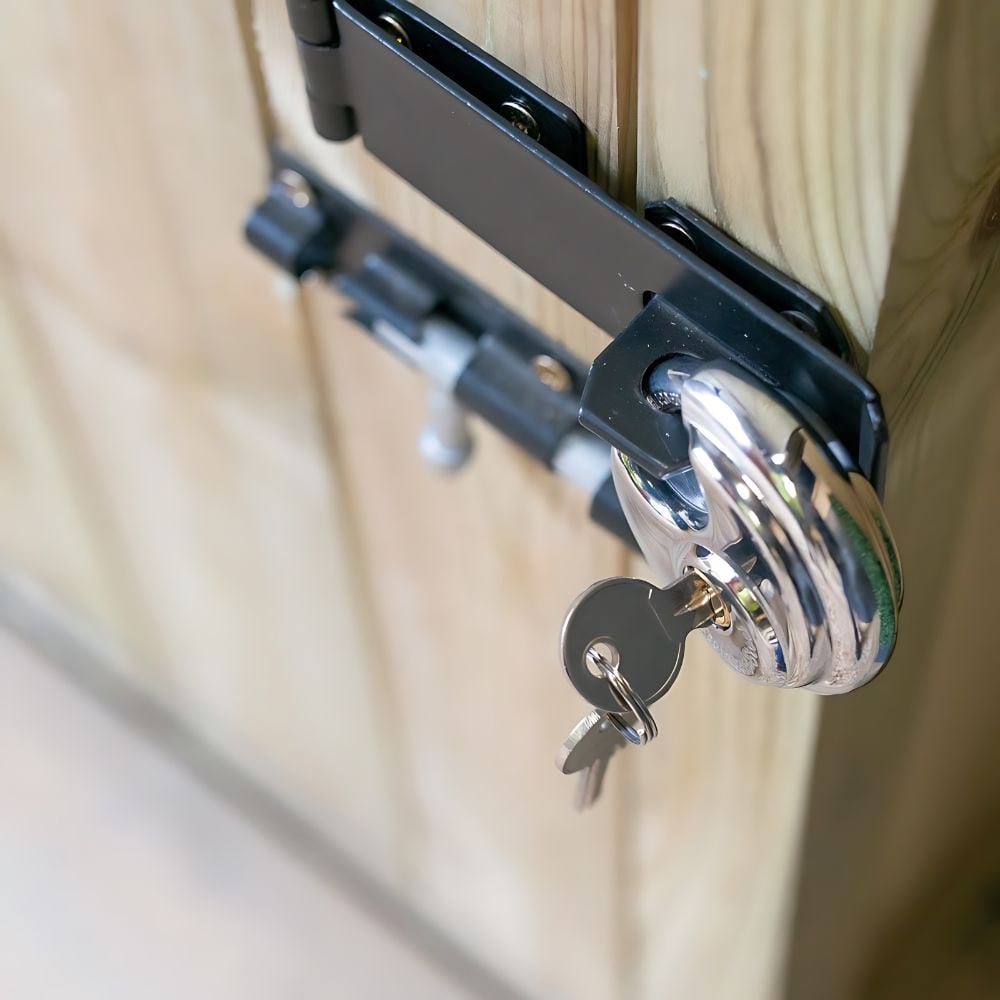 silver hanging padlock on a black metal bolt lock with keys attached