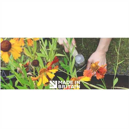 Flowers in garden with someone installing garden border