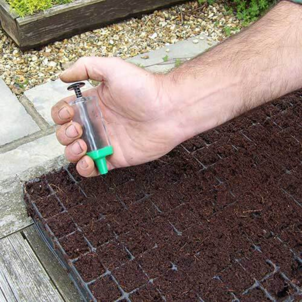 magic seeder tool  in use in someone's hand placing seeds