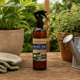 Healmybug spray bottle on a wooden surface with plants and gardening tools in the background