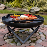 a black metal firepit style grill on diagonal legs on cobbled patio