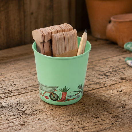 Mint Green tin on a table with plant labels and a pencil, set on a rustic wooden table.