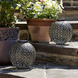 Two moroccan lanterns sat on stone step with plant pots in background