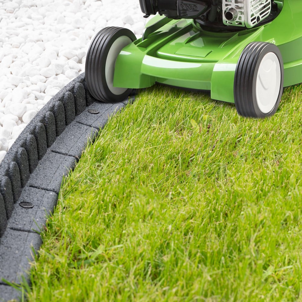 Green lawn mower cutting grass along a concrete border