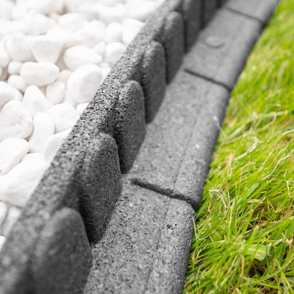 Concrete block border between white pebbles and green grass