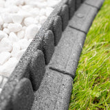 Concrete block border between white pebbles and green grass