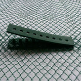 A green net clamp with multiple holes for securing netting, placed on a mesh net background.