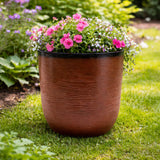 Brown planter with pink and white flowers on a grassy lawn