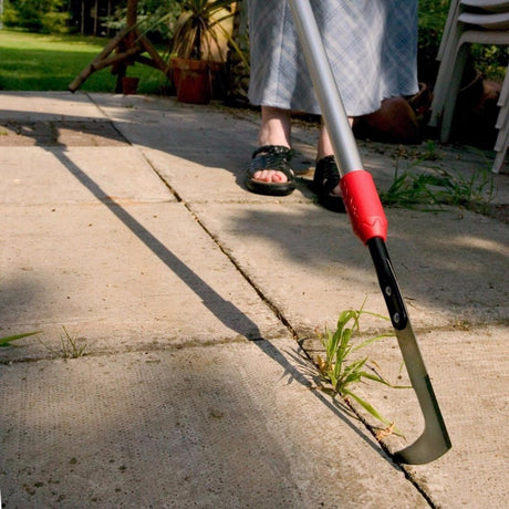 Patio weeding knife being used to remove weeds from patio