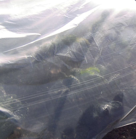 A close-up view of a white fleece cover for garden hoops, showing the texture and weave of the fabric.