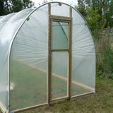 Small greenhouse with a door in a garden setting