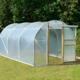 Polycarbonate greenhouse on a grassy area with trees in the background