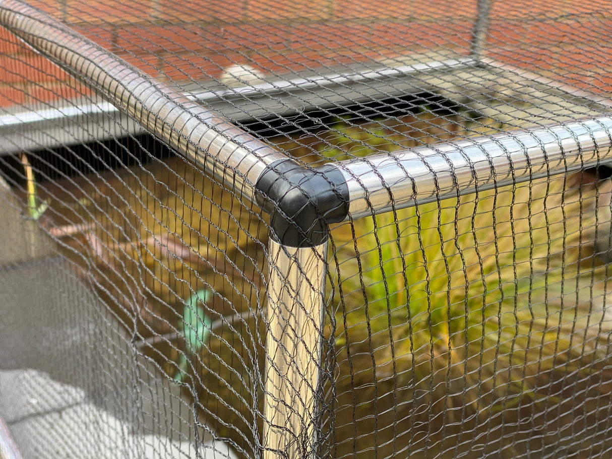 Close-up of black pond netting material with a blurred background of foliage.