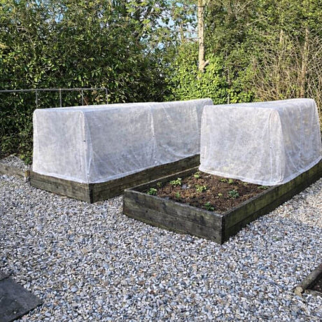 Two raised garden beds garden fleece covers in a garden