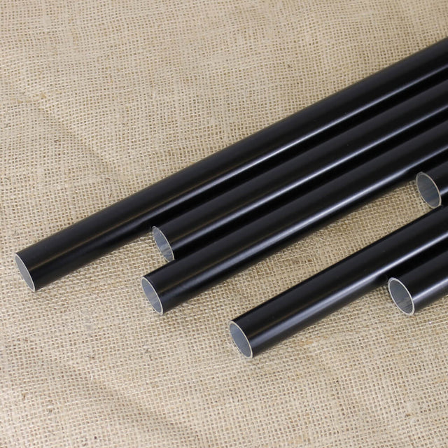 A collection of black powder coated fruit cage aluminium poles of various lengths laid out on a textured fabric surface.