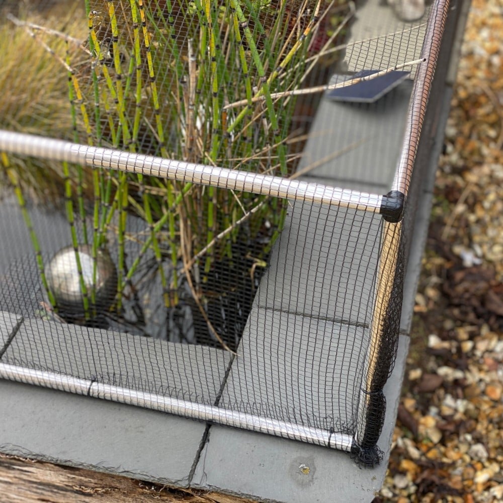 corner of an aluminium pond protection frame with black butterfly netting protection