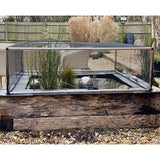 aluminium frame covering with black butterfly netting raised above a pond with pond plants growing through the netting