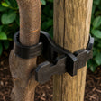 A black rubber tree tie designed to hold trees to supporting stakes, shown around a tree trunk.