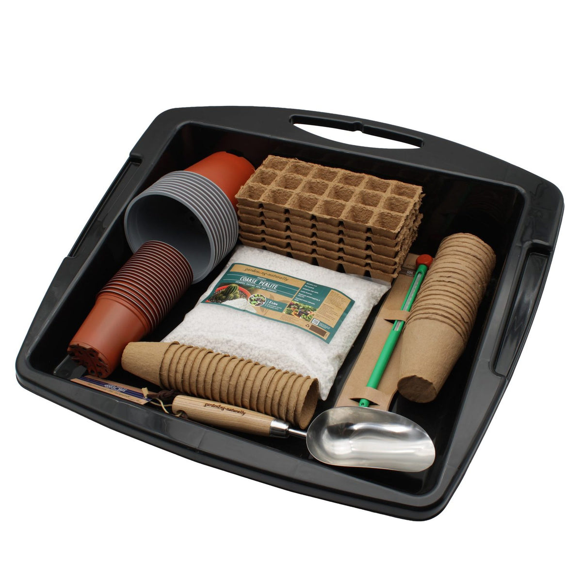 A black plastic seed-starting kit tray containing various gardening tools and starter elements, including peat pots, soil plugs, seed starting mixes, and a metal scoop, photographed on a white background.