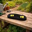 Roll of garden hose on a wooden table with gardening tools in a garden setting