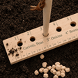 Wooden planting guide with soil and seeds on a dark background