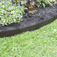 A black, metal landscaping border kit installed around a flowerbed, with green grass in the foreground.