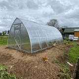 Polycarbonate greenhouse with chickens around on a cloudy day