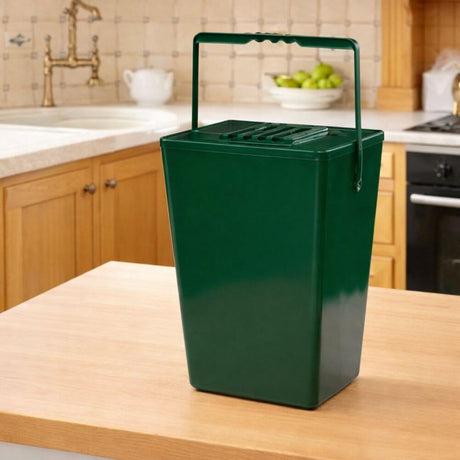 Green compost bin on a kitchen counter with apples in the background