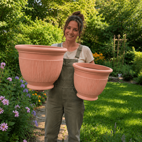 Person holding two large terracotta planters in a garden setting