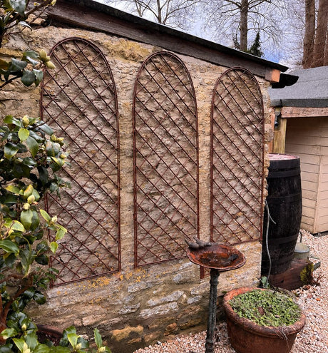 Wooden trellis against a stone wall with garden elements.