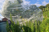 A fruit tree netting bag made of fine mesh material, covering a tree with apples, providing protection against pests and birds.