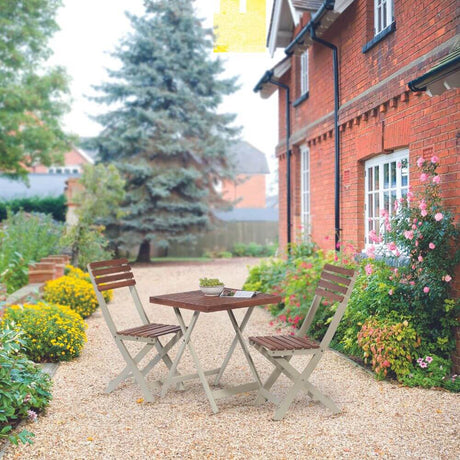 An outdoor setup with a small table and two chairs placed on a gravel garden.