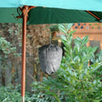 A gray, fabric wasp repeller hanging from a green umbrella, surrounded by greenery in the background.