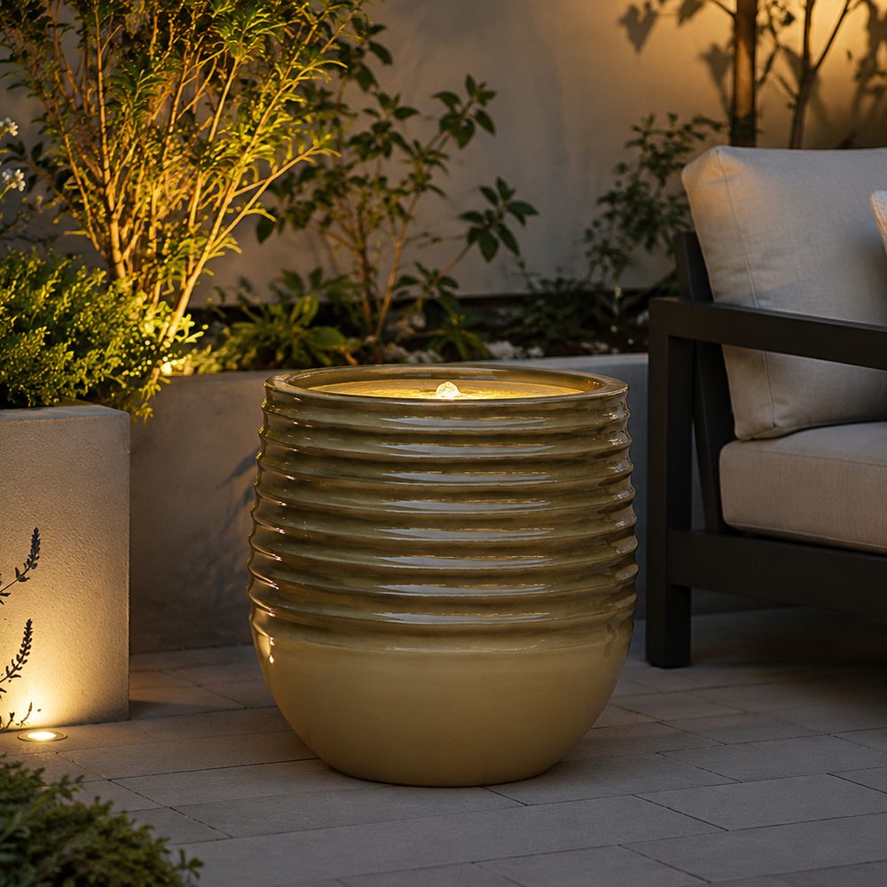 Decorative outdoor pot with a light inside, surrounded by plants and a chair.