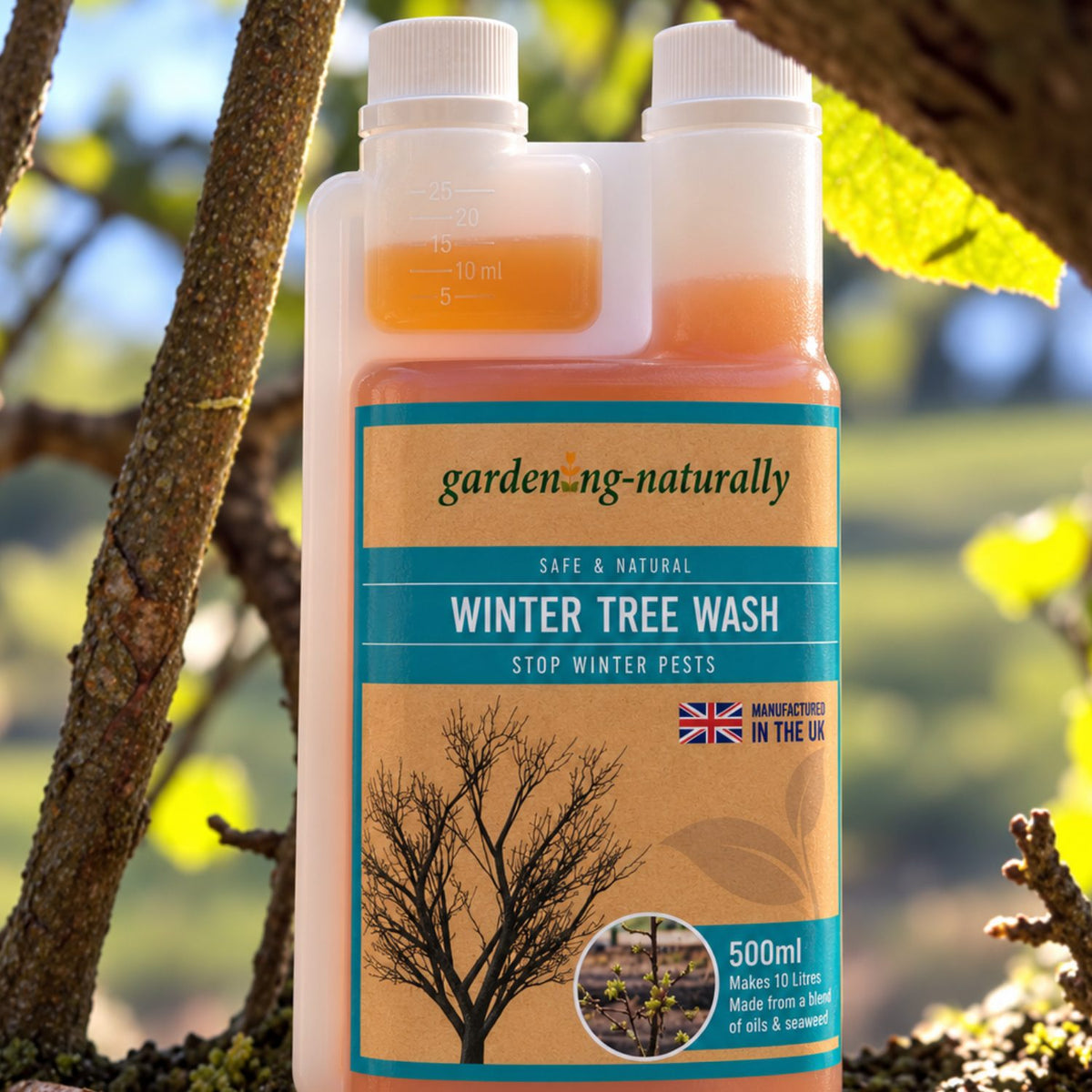 A 500ml bottle of gardening-naturally Winter Tree Wash standing outdoors on tree branches with blurred green leaves and sunlight in the background.